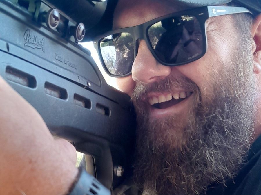 A grinning bearded player takes a selfie with his laser tag gun