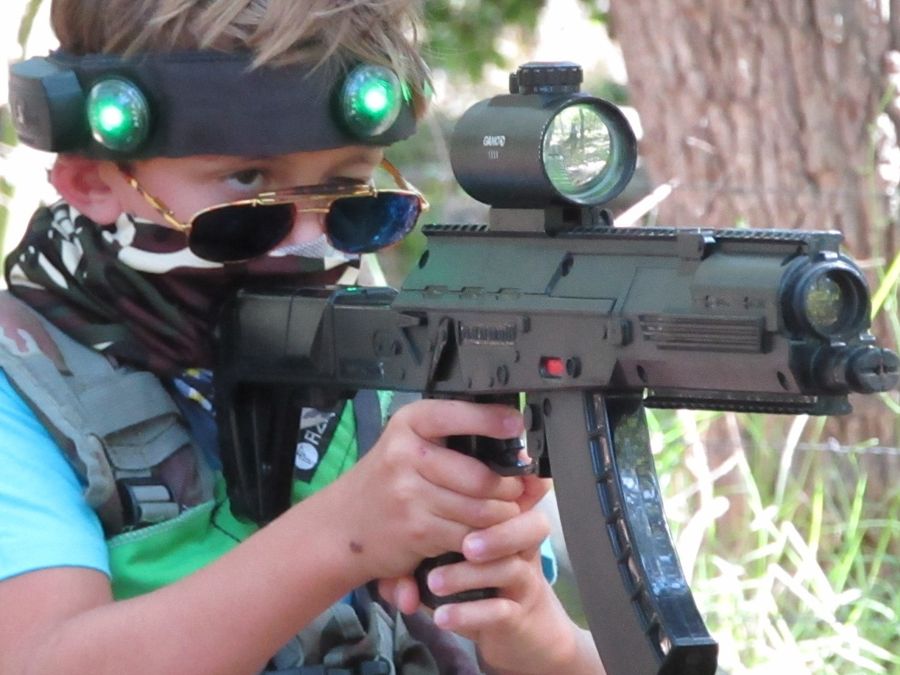 A boy in a vibrating hit headband aims his laser tag rifle