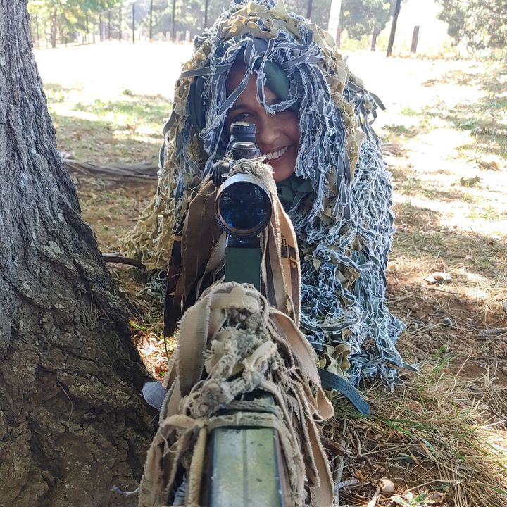 A sniper in a ghillie suit aiming straight at the camera