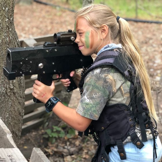 A girl in camo face paint aims her rifle