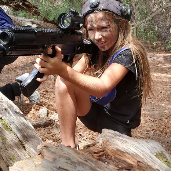 A girl crouches and aims in face paint