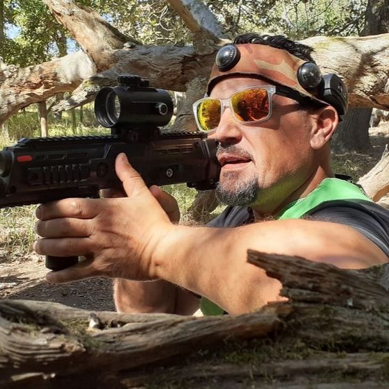 A man in a hit headband aims from cover