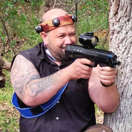 A tattooed player aims his rifle